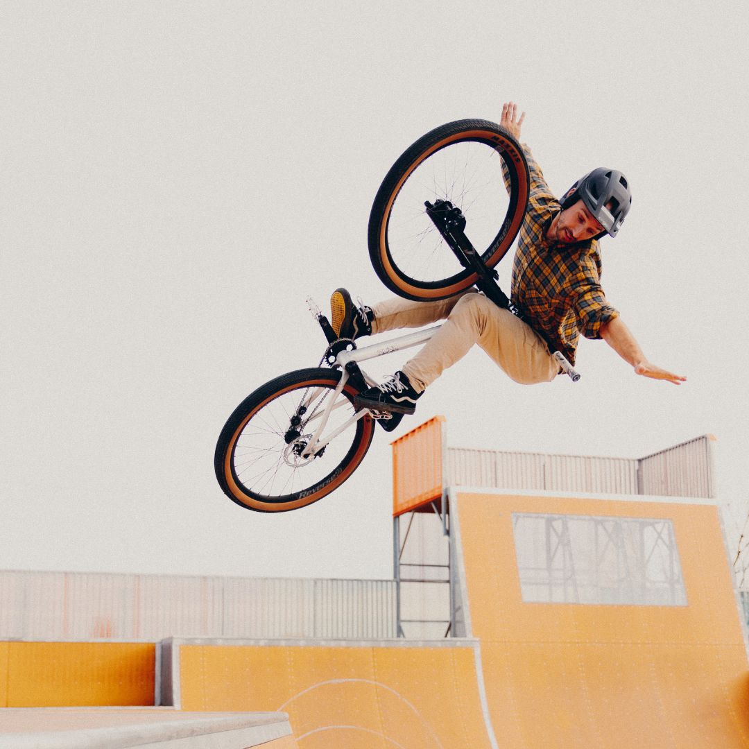 Homme effectuant une figure en BMX dans un skatepark.