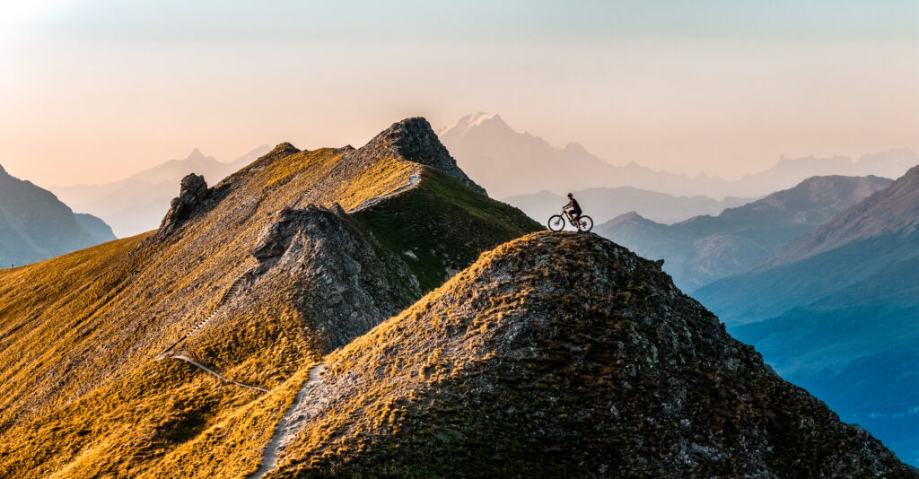 Cycliste sur sommet montagneux au crépuscule.