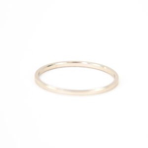 Anneau en or minimaliste sur fond blanc.