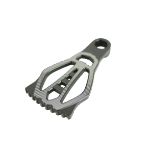 Grattoir métallique avec motifs géométriques, fond noir.