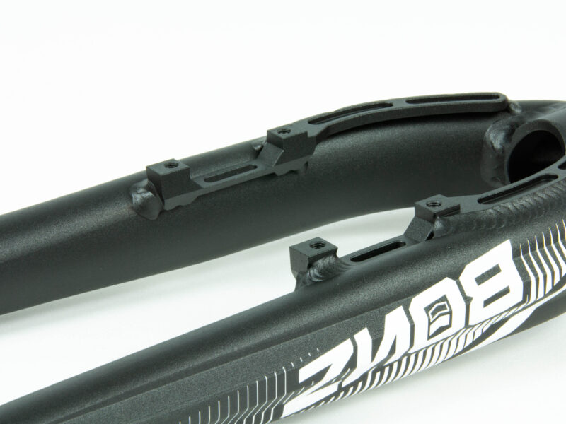 Fourche de vélo noire avec fixations et logo blanc.